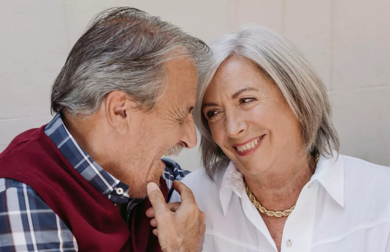 Una pareja octogenaria mirándose y riendo